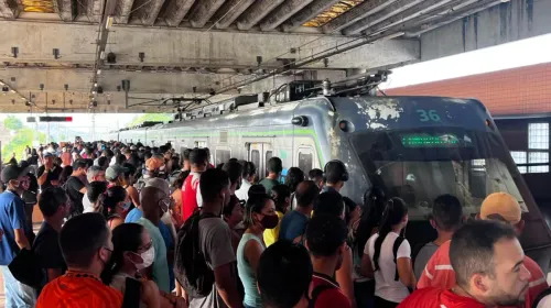 Plataforma de estação de metrô lotada de passageiros ao redor de um trem parado. A multidão ocupa quase todo o espaço disponível próximo às portas do vagão.