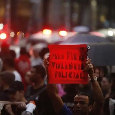 Homem segura cartaz dizendo "Pelo fim da violência policial" em protesto